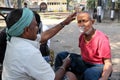 Street barber shaving a man using an open razor blade on a street in Kolkata