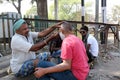 Street barber shaving a man using an open razor blade on a street in Kolkata