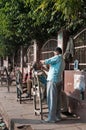 Street barbers shaving men on the street in market. Agra. India