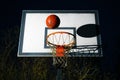 Street basketball ball falling into the hoop at night. Urban youth game. Close up of orange ball above the hoop net. Concept of Royalty Free Stock Photo