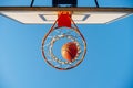 Street basketball ball falling into the hoop. Urban youth game. Close up of orange ball above the hoop net. Concept of success, Royalty Free Stock Photo