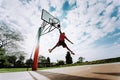 Street basketball player making a powerful slam dunk on the court - Athletic male training outdoor at sunset