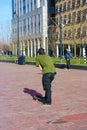 Street boy raised in the modern metropolis of Rotterdam in the Netherlands. Young man practices his skateboard in a square among