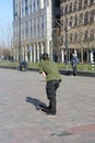 Street boy raised in the modern metropolis of Rotterdam in the Netherlands. Young man practices his skateboard in a square among
