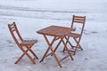 Street brown wooden table and wooden chairs on a snowy street