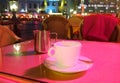 Evening in city street cafe cup of coffee on table pink colored  night light bokeh Royalty Free Stock Photo
