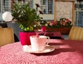 Street Cafe on table cup of coffee and pink flowers pink coral tablecloth on the table and yellow chair cloth morning breakfast