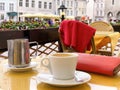 Street Cafe Table  with cup of coffee and yellow and pink flowers  , red wallet Town Square in Old Town Of Tallinn Summer Day cit Royalty Free Stock Photo