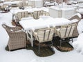 Street cafe with wooden tables and wicker chairs and armchairs strewn with snow Royalty Free Stock Photo