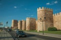 Street with cars beside stone towers in the walls around Avila