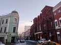 A street in the center of Moscow, a house of light green color and a red theater building in the Russian style,