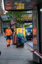 Street cleaner in orange reflective clothing with dust cart outside Waterloo Station