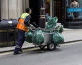Street cleaner pushing his trolley with bags