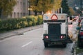 Street cleaner vehicle sweeping the roads in the city. Street sweeper machine making problems in the morning traffic Royalty Free Stock Photo