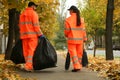 Street cleaners with brooms and garbage bags outdoors on autumn day, back view Royalty Free Stock Photo