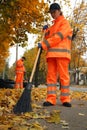 Street cleaners sweeping fallen leaves outdoors on autumn day Royalty Free Stock Photo