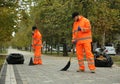 Street cleaners sweeping fallen leaves outdoors on autumn day Royalty Free Stock Photo