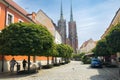 Street with cobblestone road with green trees, colorful buildings, summer cafe, Cathedral of St. John the Baptist church Royalty Free Stock Photo