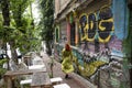 Street coffee sidewalk bar with colorful graffiti facade wall and redhead woman in green dress walking by