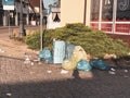 In street corner many garbage bags stand side by side and loose garbage lies around