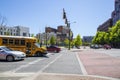 A street corner with Miller Park, traffic signals, a yellow school bus, cars and trucks, lush green trees, office buildings