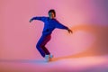 Street dance style. Happy black female hip-hop dancer dancing in neon pink lights, studio background, free space Royalty Free Stock Photo