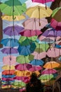 Street decoration with colorful open umbrellas hanging between buildings over the alley