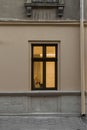 Street exterior view with beige wall and window frame with lamp yellow light from inside vertical outdoor photo Royalty Free Stock Photo