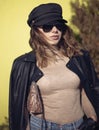 Street fashion outdoor photo of woman with dark hair in black leather jacket and sunglasses, snake bag Royalty Free Stock Photo