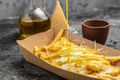 Street and fast food, paper box with fried potato frit chips and mayonnaise sauce on a dark background