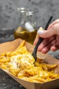 street and fast food, paper box with fried potato frit chips and mayonnaise sauce on a dark background