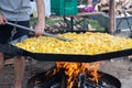 Street festival of potatoes in Germany. Traditional fried potatoes with onions over an open fire in a huge frying pan. A man is Royalty Free Stock Photo