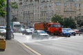 Street flusher machine and vehicles riding on the road in the city. Watering machine washes the road dust and dirt