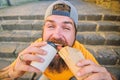 Street food concept. Man bearded eat tasty sausage and drink paper cup. Urban lifestyle nutrition. Junk food. Carefree Royalty Free Stock Photo