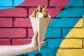 Street food dessert Belgian waffles in hand on a colored wall background. Sweets, street food