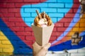 Street food dessert Belgian waffles in hand on a colored wall background. Sweets, street food