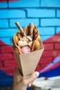 Street food dessert Belgian waffles in hand on a colored wall background. Sweets, street food