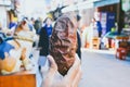 Male hand holding Japanese roasted sweet potato with blurred street food market background