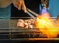 A man grilling slice of meat on the stove with flame from gas pipe Royalty Free Stock Photo