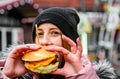 Street food. young woman holding juicy burger and eating oudoor