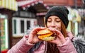 Street food. young woman holding juicy burger and eating oudoor