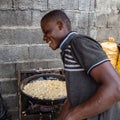 Street foods in Lagos Nigeria; happy vendor frying akara along the street.