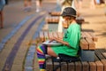 Street hank drum musician, young girl sitting on street bench and playing music on steel tongue drum