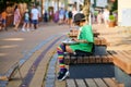 Street hank drum musician, young girl sitting on street bench and playing music on steel tongue drum