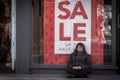Street homeless man in front of for sale sign
