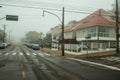 Street with houses and parked cars on a foggy day