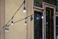 Street illumination decoration. Garland of light bulbs. Street stretch marks against background of window with forged bars.