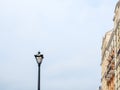 Street lamp against the background of a cloudy sky and a fragment of a building