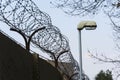 Street lamp beside barbed wire fence stretched around prison walls Royalty Free Stock Photo