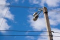 Street lamp on a concrete pillar against a bright blue sky with clouds and wires Royalty Free Stock Photo